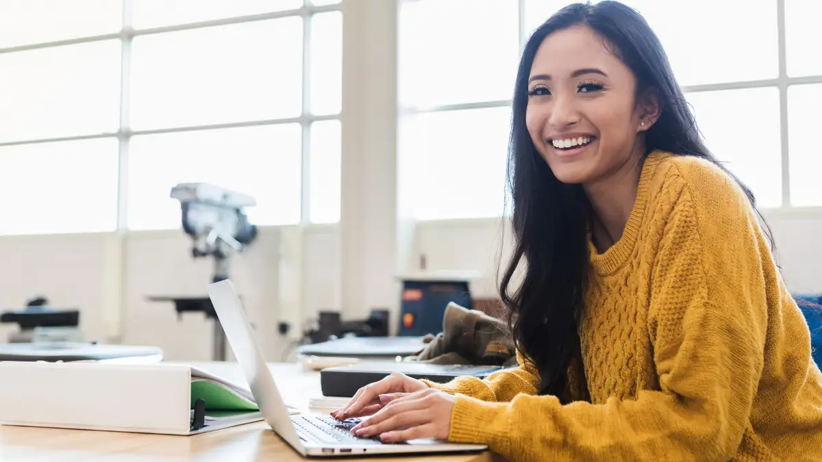Perempuan muda belajar dengan laptop di ruang kelas