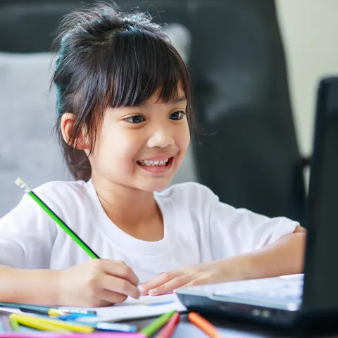 Seorang anak menulis di meja belajar, foto dari Noble Academy